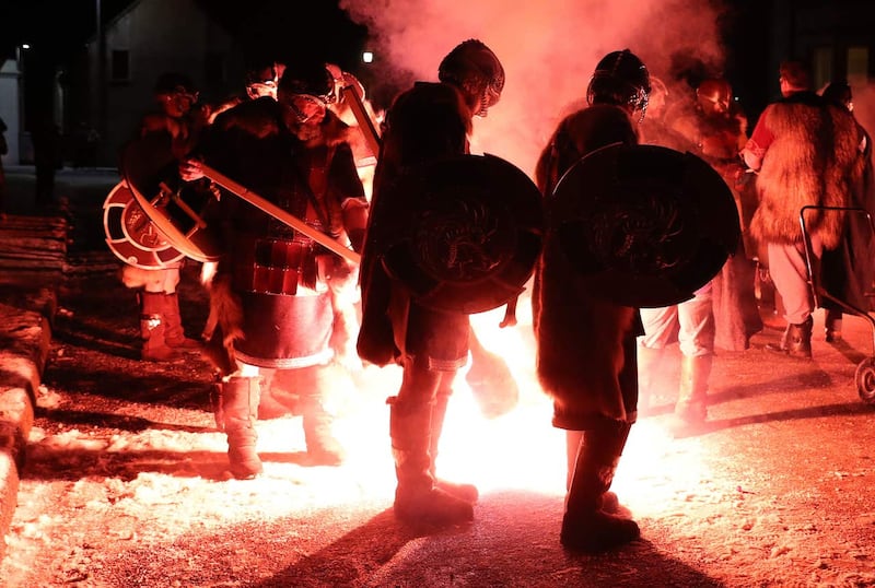 A flare is fired to light the torches of the Jarl Squad as they march through Lerwick ahead of the Galley being set on fire on Shetland Isles during the Up Helly Aa Viking festival 