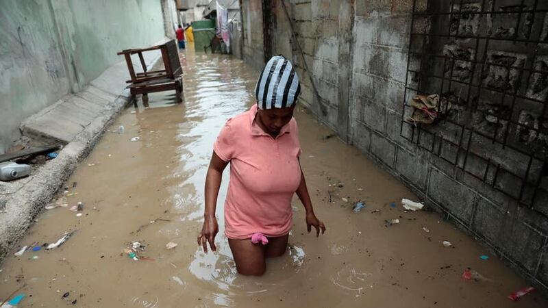 A woman walks through a flooded alleyway after heavy rain in Port-au-Prince (AP Photo/Odelyn Joseph)