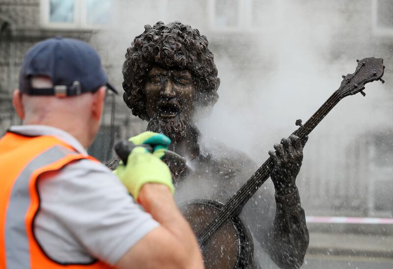 Ross Sheridan of P.Mac Cleaning and Restoration services working on behalf of Dublin City Council cleans a statue of the late musician Luke Kelly on King Street South in Dublin's city centre after it was defaced overnight. Picture by Brian Lawless/PA Wire&nbsp;