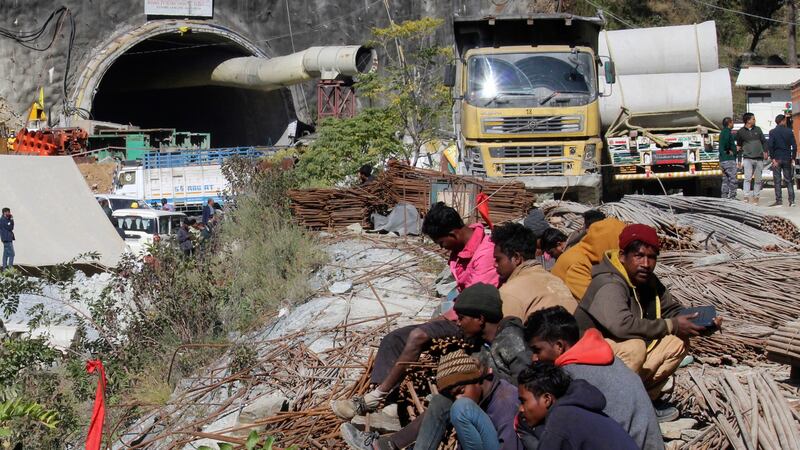 People sit near the site of the tunnel that has collapsed (AP/PA)