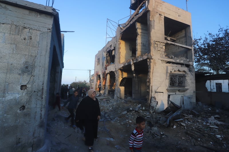 Palestinians walk by a residential building destroyed in an Israeli strike in Rafah (Hatem Ali/AP)