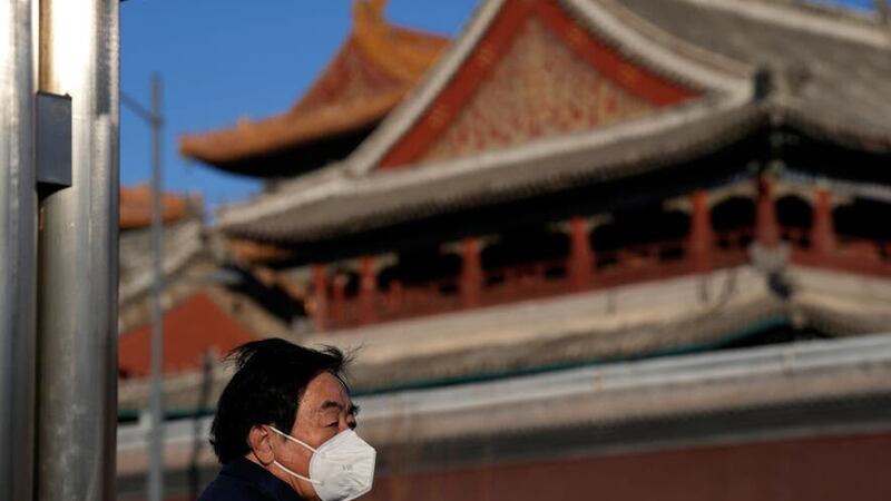 A resident wears a mask as he stands near a temple in Beijing (Ng Han Guan/AP)