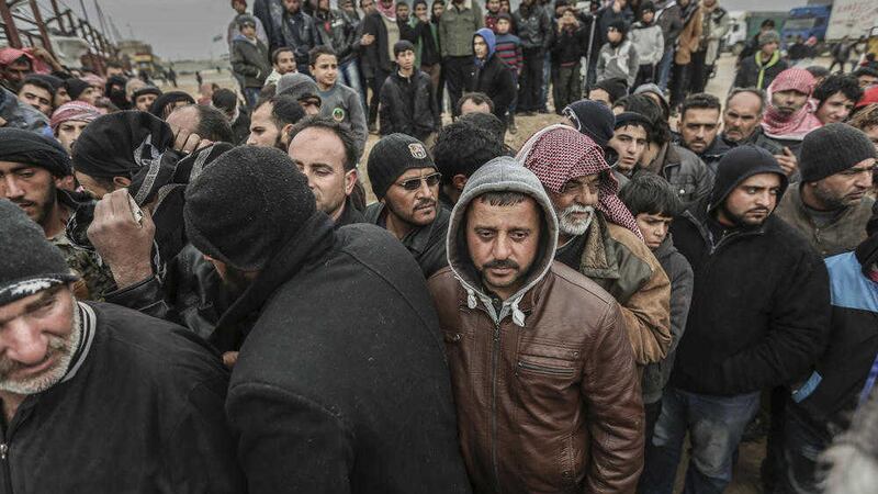 Syrians gather at a border crossing with Turkey at the weekend as thousands of people fled a government offensives and Russian airstrikes 