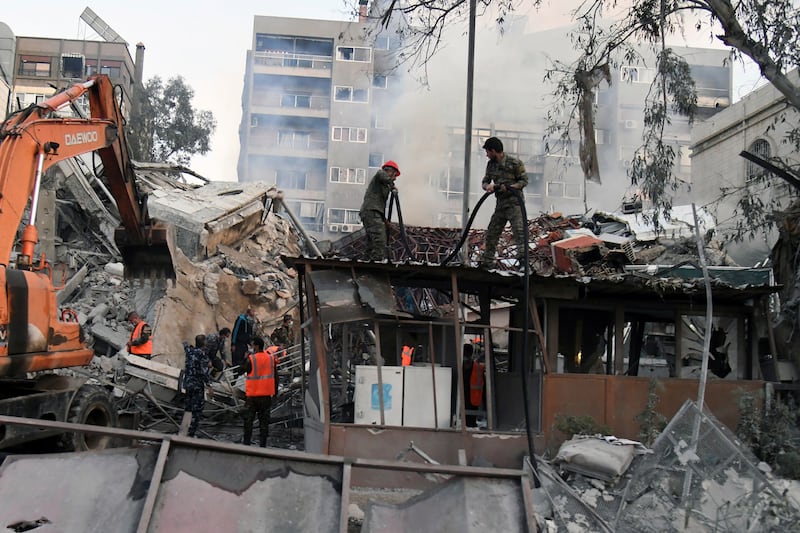 Emergency workers clear the rubble of a building in Damascus destroyed in an Israeli air strike (Sana/AP)