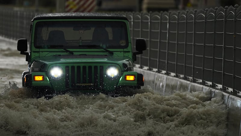 An SUV passes through water in Dubai (Jon Gambrell/AP)