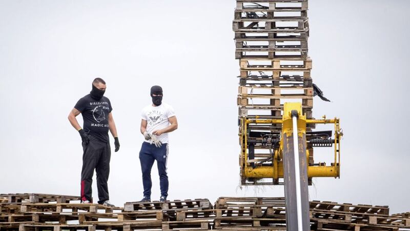 Masked men add to a bonfire at Inverary Playing Fields in east Belfast in apparent defiance of a court injunction 