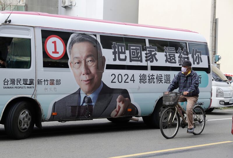 A man rides past a bus with a poster of Taiwan People’s Party (TPP) presidential candidate Ko Wen-je (Chiang Ying-ying/AP)