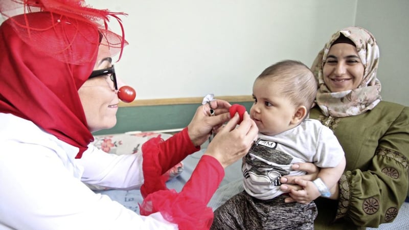 One of the Red Noses Palestine Clown Doctors makes a young patient and his mother smile Picture: Sean McKernan 