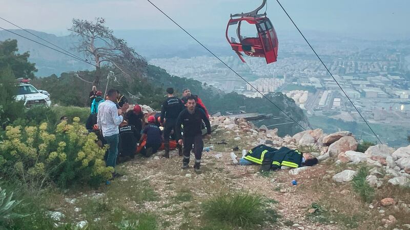 Rescue and emergency team members work with passengers of a cable car (Dia Images via AP)