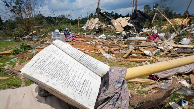 A prayer book rests on a parking barrier among the debris (Rogelio V Solis/AP)