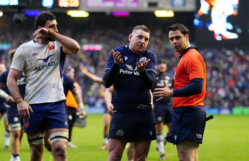 Finn Russell (middle) speaks to assistant referee Nika Amashukeli as they wait for a TMO decision on the Scotland try that was not given