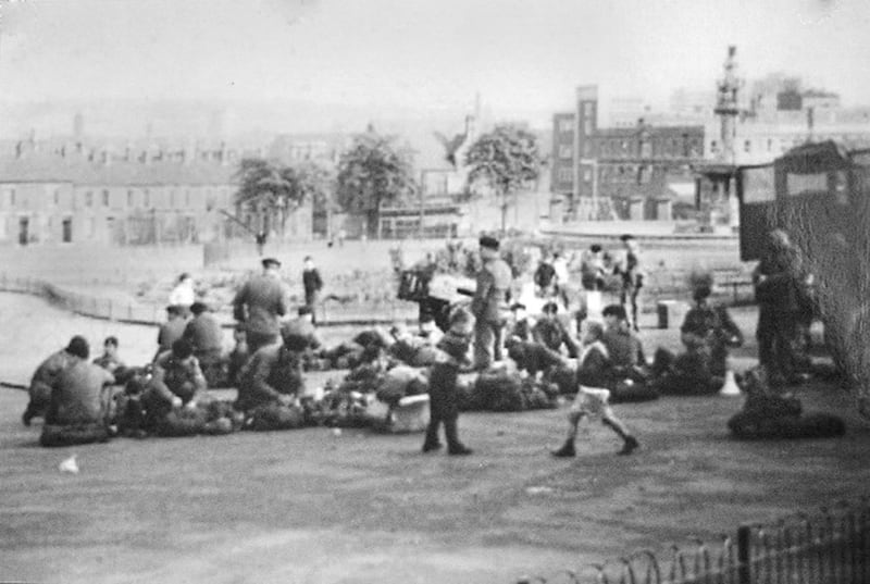 Children play in Dunville park in west Belfast while British soldiers rest after the burning of Bombay Street August 1969 