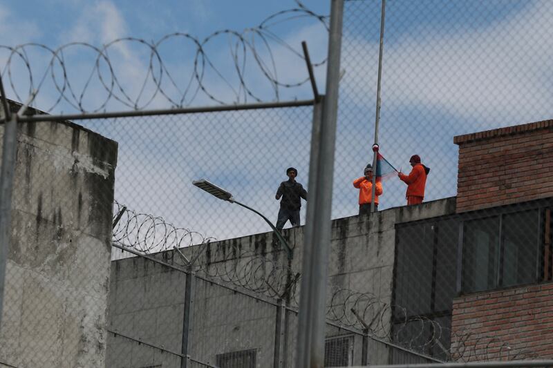 Inmates stand on the top of Turi jail during a prisoner riot in Cuenca, Ecuador (Xavier Caivinagua/AP)