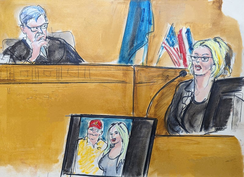 In this courtroom sketch, Stormy Daniels gives evidence as Judge Juan Merchan looks on in Manhattan criminal court. A photo of Donald Trump and Daniels from their first meeting is displayed on a monitor (Elizabeth Williams via AP)