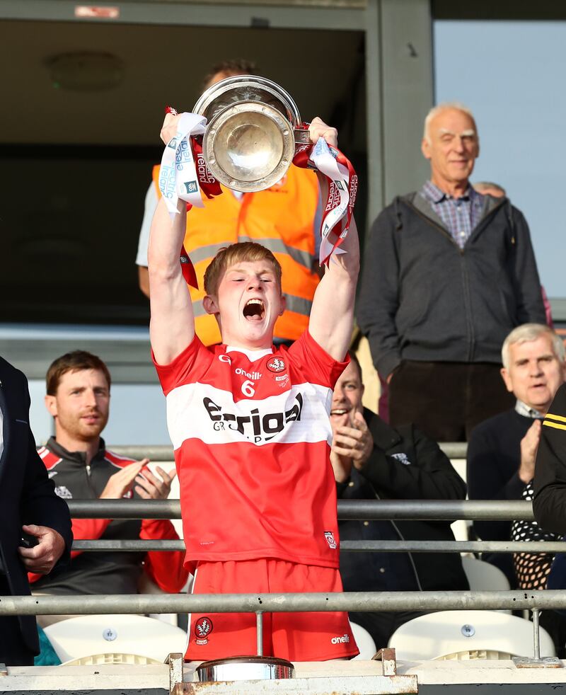 Derry captain Fionn McEldowney lifts the Fr Murray Cup after their Ulster MFC final win over Monaghan last month, watched by Gerard O’Kane (left), who lifted the same silverware before going on to claim the Tom Markham Cup for Derry as All-Ireland champions in 2002       Picture: Philip Walsh