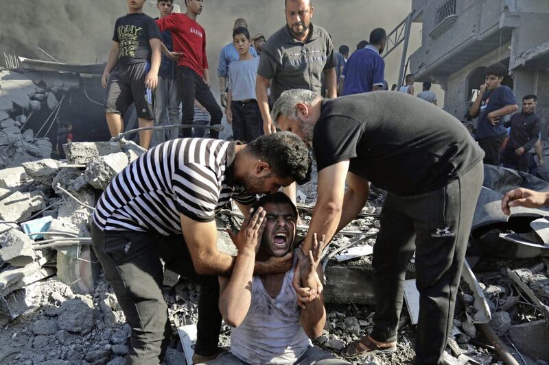Palestinians comfort a crying man after losing relatives under the rubble of a destroyed house following an Israeli airstrike in Gaza City