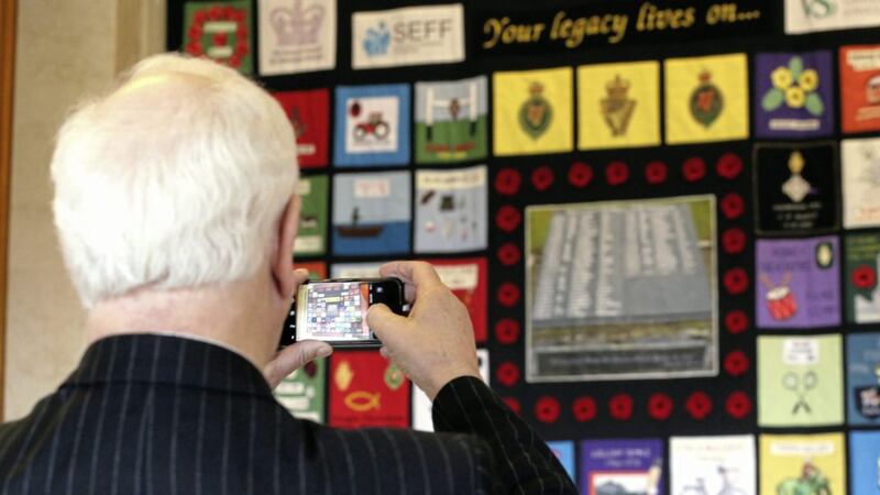 A visitor takes a picture of a quilt which honours victims of the Troubles at the Memorial Quilt exhibition at Stormont yesterday. Picture by Stephen Davison/ Pacemaker 