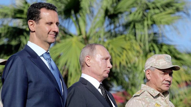 From left, Syrian President Bashar Assad, Russian President Vladimir Putin and Russian Defence Minister Sergei Shoigu watch the troops marching at the Hemeimeem air base in Syria last year 