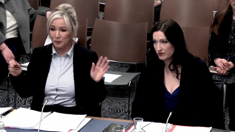 Michelle O'Neill (left) and Emma Little-Pengelly (right) sitting at a table talking to a committee out of shot