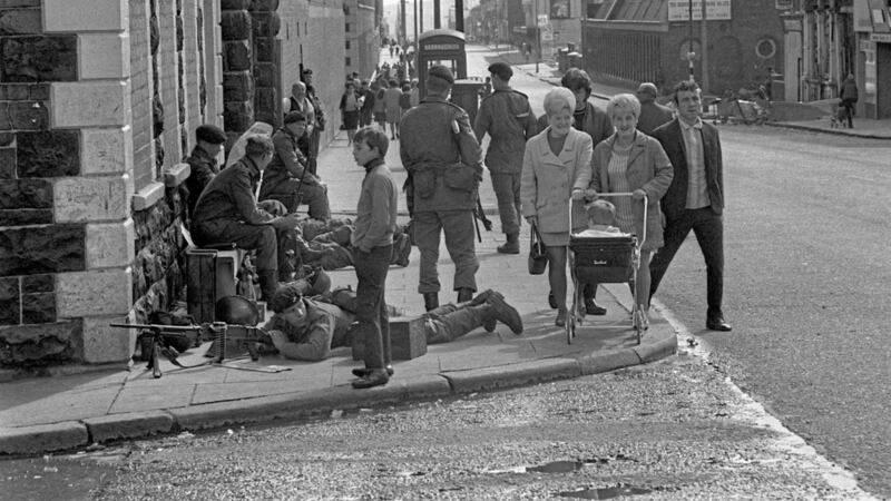 A photo taken in August 1969 of women on Crumlin Road in north Belfast pushing a pram around the legs of a soldier laying with his Bren Gun trained on Hooker Street. Picture by Press Association 