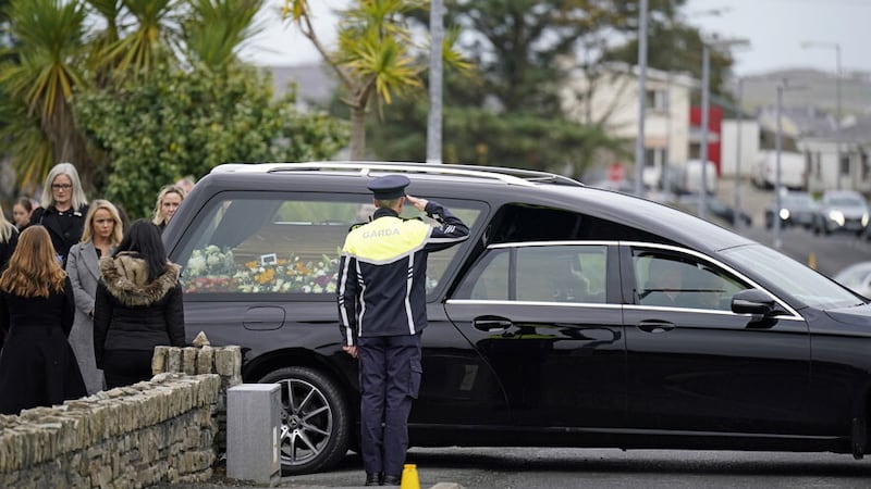 A member of An Garda Síochána salutes as the coffin of James O'Flaherty arrives at St Mary's Church, Derrybeg for his Requiem Mass. Picture by Niall Carson, Press Association 
