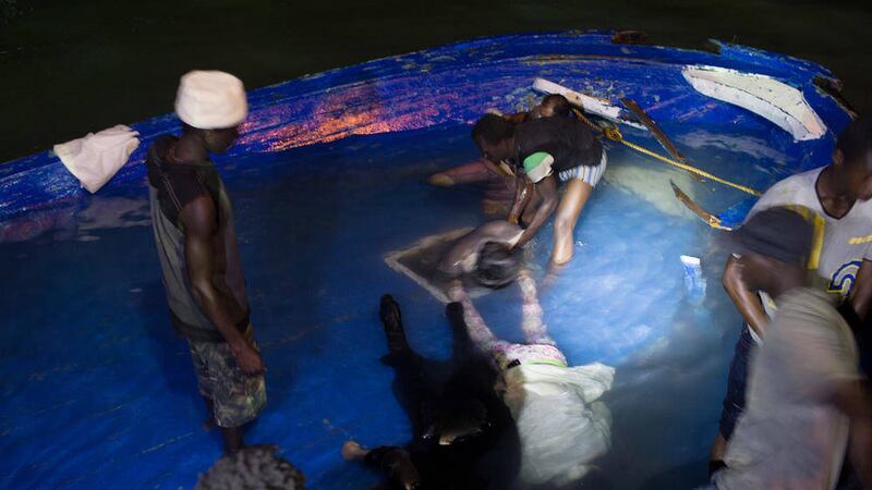 The body of a drowned migrant is pulled from the bottom of a boat that sank of the coast in Zuwara, Libya.  
