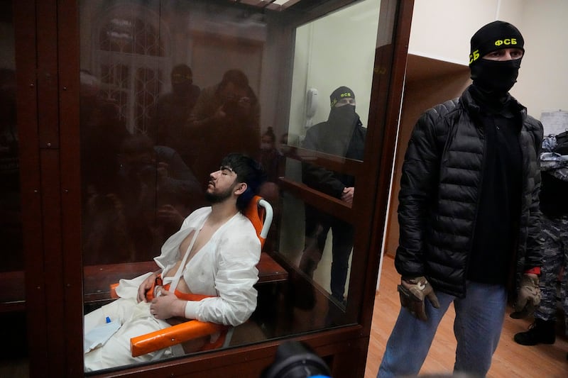 Mukhammadsobir Faizov, a suspect in Friday’s shooting, attended court in a wheelchair and sat with his eyes closed throughout. He was attended to by medical personnel, wore a hospital gown and appeared to have multiple cuts (AP Photo/Alexander Zemlianichenko)