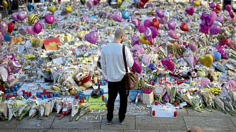 A man stands next to flowers for the victims of the Manchester bombing PICTURE: Emilio Morenatti/AP