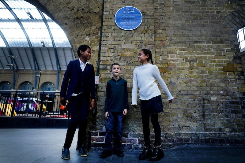 Josiah Jackson, Lawrence Hollingsworth and Sofia Hollingsworth stand below a plaque to commemorate their great grandfather
