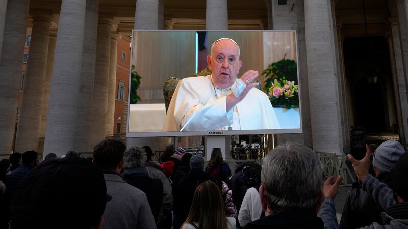 A giant screen broadcasts Pope Francis delivering his blessing during the noon prayer from the chapel of the hotel at the Vatican grounds where he lives (AP Photo/Alessandra Tarantino)