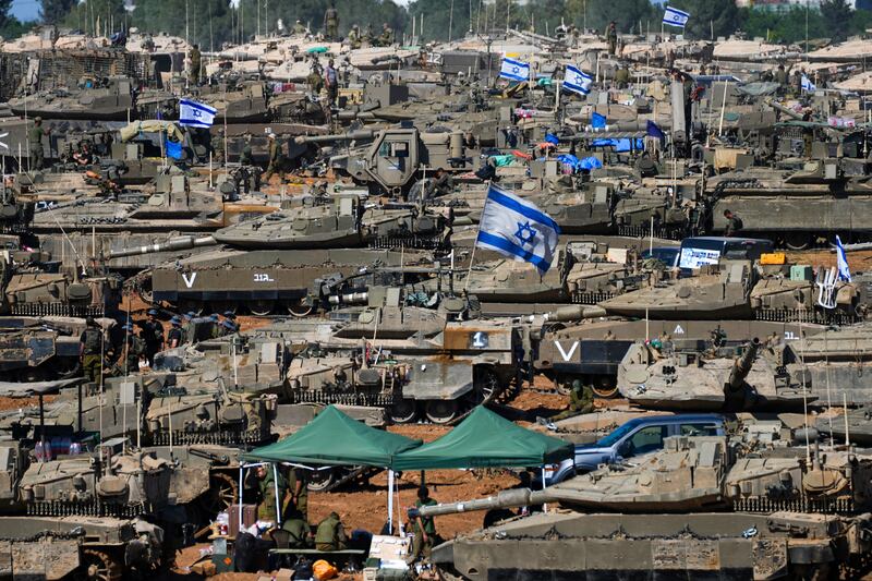 Israeli soldiers work on armoured military vehicles at a staging ground near the Israeli-Gaza border, in southern Israel (AP Photo/Tsafrir Abayov)