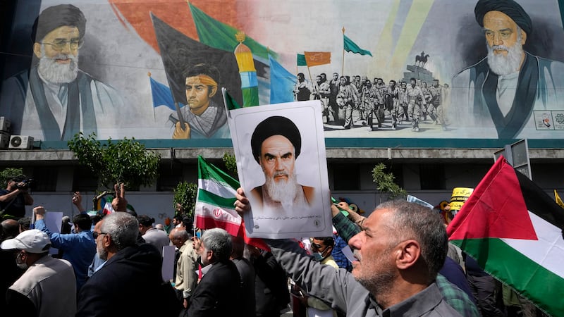 Iranian worshippers walk past a mural showing the late revolutionary founder Ayatollah Khomeini (AP)