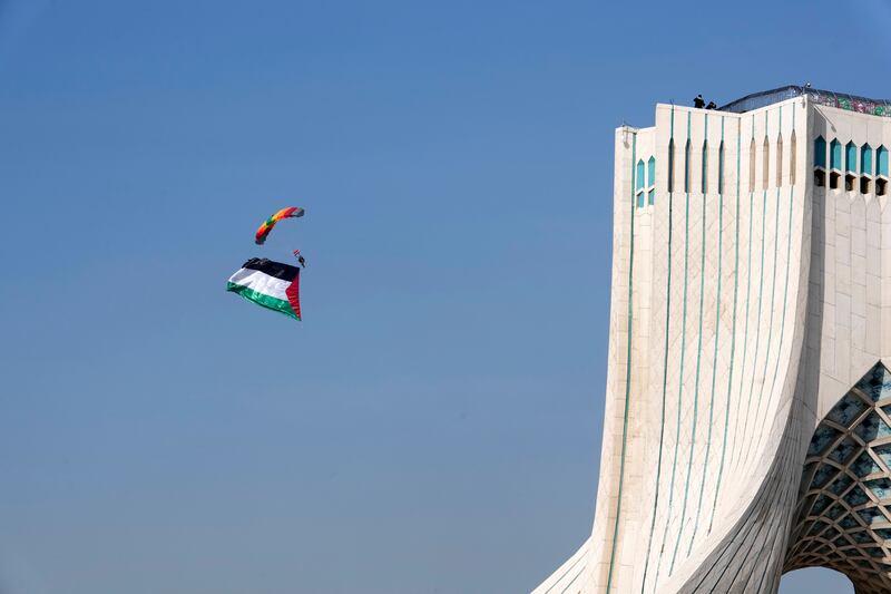 An Iranian paratrooper carrying a huge Palestinian flag floats near the Azadi (Freedom) monument tower in Tehran (Vahid Salemi/AP)