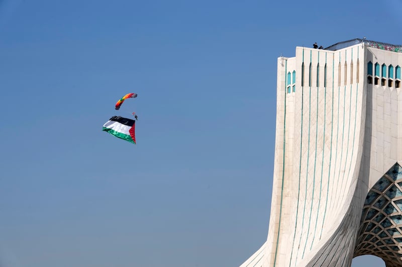 An Iranian paratrooper carrying a huge Palestinian flag floats near the Azadi (Freedom) monument tower in Tehran (Vahid Salemi/AP)