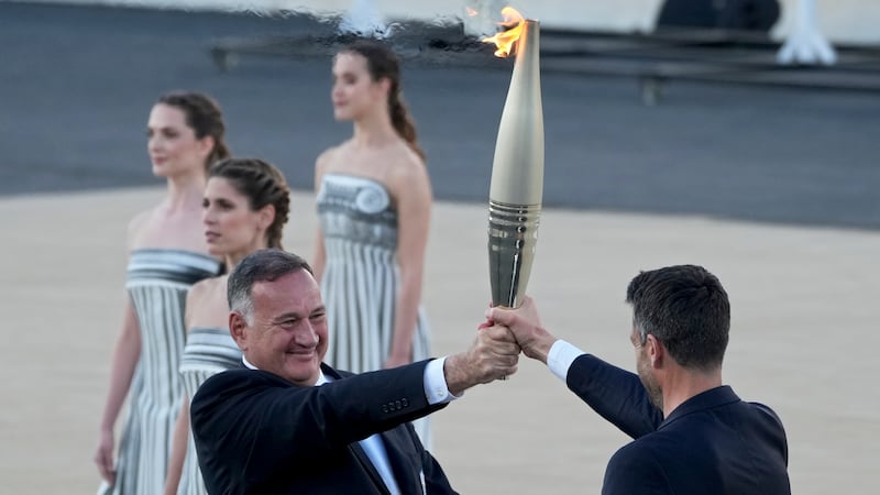 Tony Estanguet, president of Paris 2024, right, receives the Olympic flame from Spyros Capralos, head of Greece’s Olympic Committee, during the flame handover ceremony at the Panathenaic Stadium in Athens (Petros Giannakouris/AP)