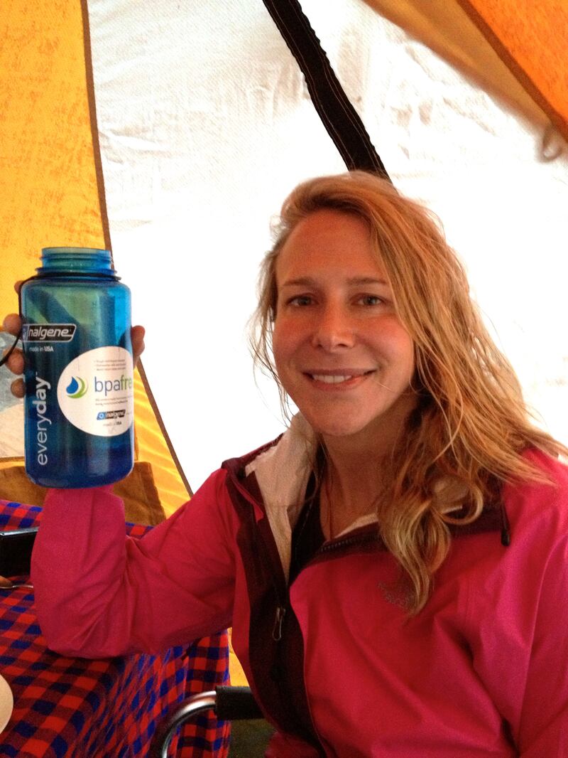 Vanessa holds a bottle at Mount Kilimanjaro - she is wearing a pink jacket, holding a blue bottle