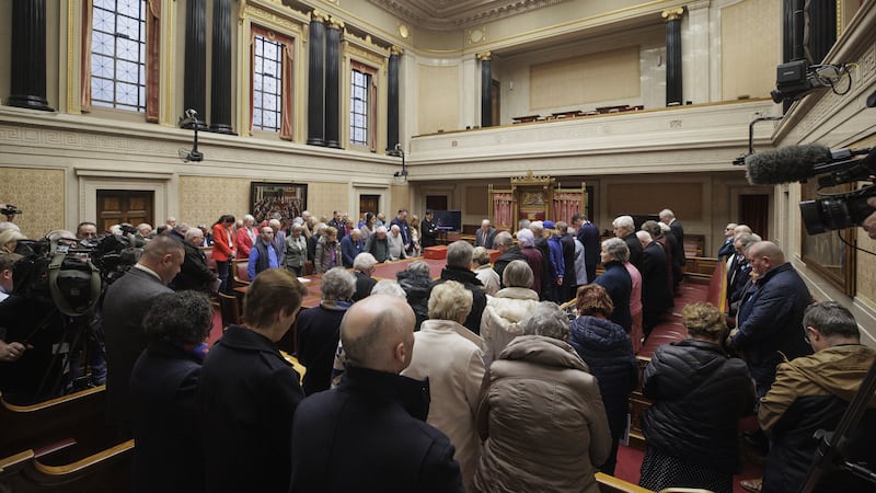 A room of people bowing their heads and observing a minute of silence during an event commemorating European Day of Remembrance of Victims of Terrorism