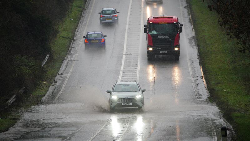 Vehicles driving through service water on a flooded part of the A37 near Bristo (Ben Birchall/PA)