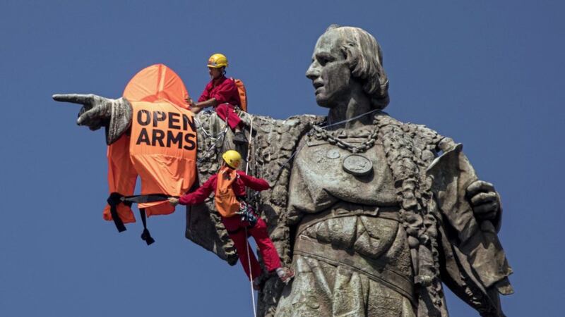 Activists climb on top of the 60 metre tall Christopher Columbus tower in Barcelona after placing a life vest bearing the words &#39;Open Arms&#39; on it, to draw attention to the loss of life of migrants and refugees in the Mediterranean Sea. The Christian response to refugees is one of the topics being addressed at the WMOF. 