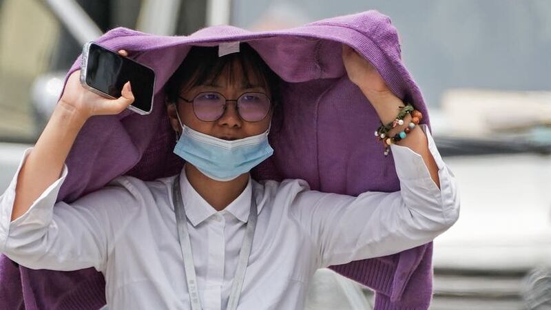 A woman uses a sweater to shield from the sun in Beijing on Monday (Andy Wong/AP)