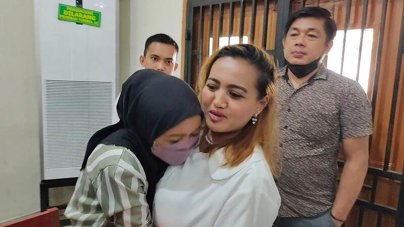 An unidentified relative hugs Lina Lutfiawati, centre, after her trial (Mohammad Fadli/AP)