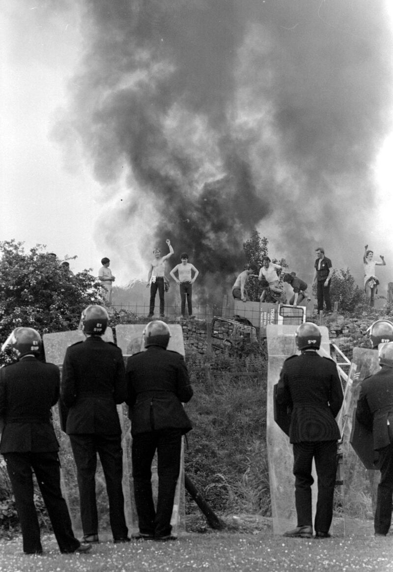 Anti-riot squad police watch as pickets face them against a background of burning cars at the Orgreave coking plant in Yorkshire in 1984