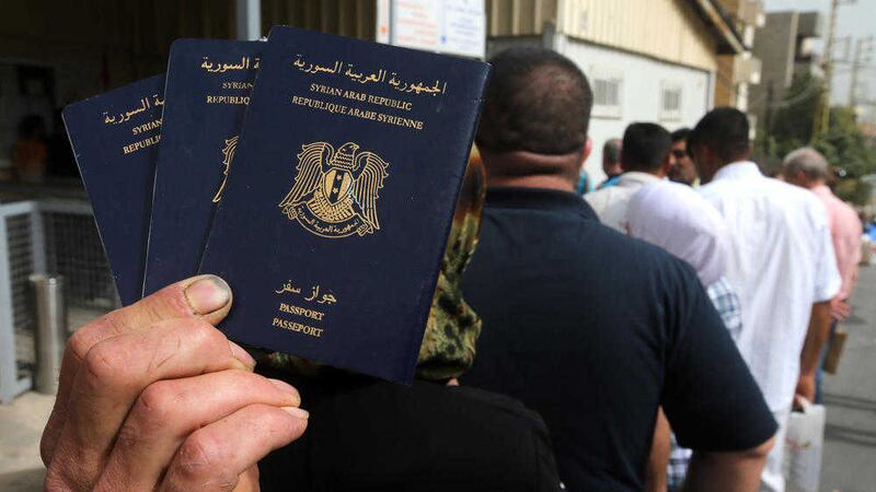 A Syrian man holds his family&#39;s passports as he lines up with other Syrians to apply for asylum visas, outside the German embassy, in Rabieh, north Beirut, Lebanon. Picture: AP /Hussein Malla 