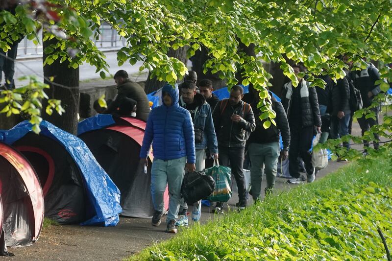 Asylum claimants remove their belongings during the operation