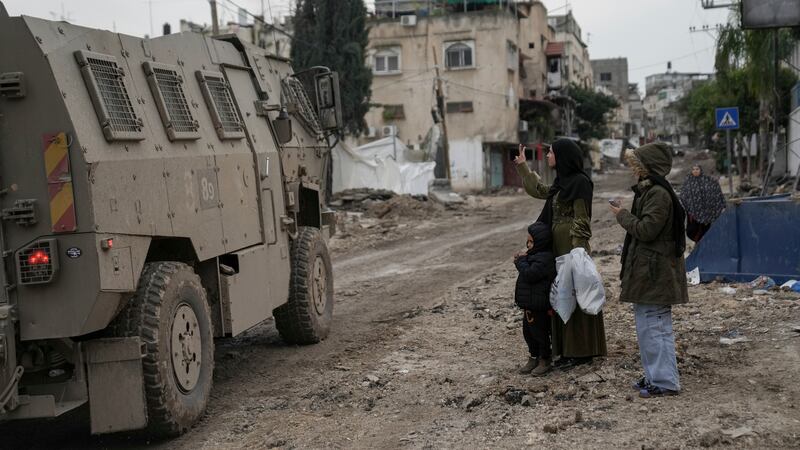 A Palestinian woman flashes a V-sign towards Israeli troops during an army raid in the Tulkarem refugee camp, West Bank, on Wednesday (Nasser Nasser/AP)