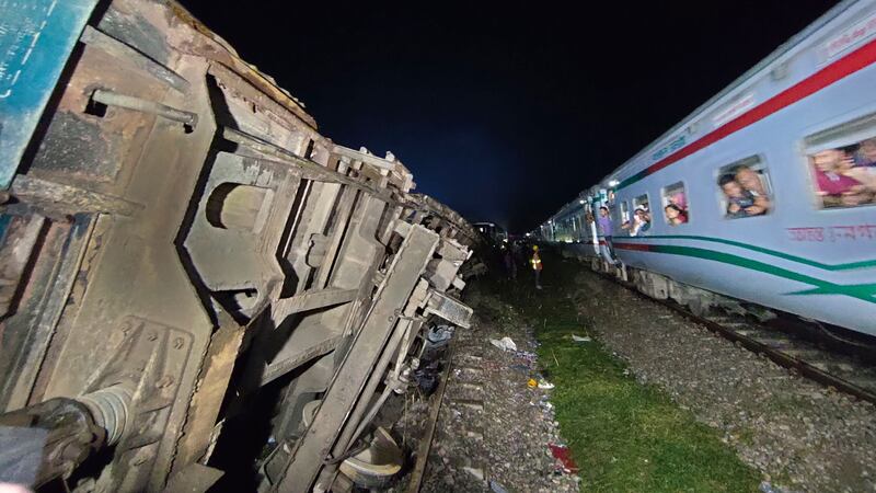 Passengers of a passing train view the crashed compartments (Mahmud Hossain Opu/AP)