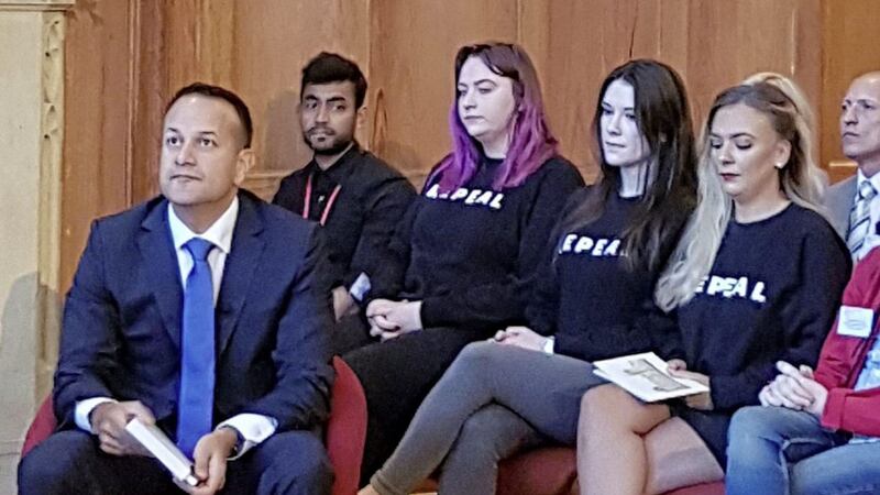 Student officers Jessica Elder, Lucy Gault and Rachel Powell sit behind taoiseach Leo Varadkar wearing Repeal jumpers in the Great Hall at Queen&#39;s University Belfast 