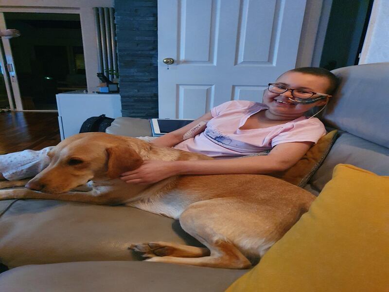 Alyssa is recovering at home and is pictured here with their family dog, Holly (Family handout/PA)