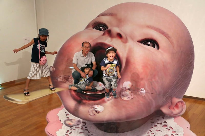 Visitors pose for a photo with a 3D image at a 3D trick art exhibition by Japanese artist Masashi Hattori in Kawasaki (Koji Sasahara/AP/PA)