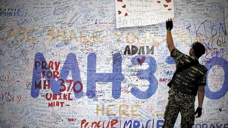 A Malaysian military soldier patrols the viewing gallery of the Kuala Lumpur International Airport where dedication boards with well wishes and messages for people involved with the missing Malaysia Airlines jetliner MH370 is displayed 